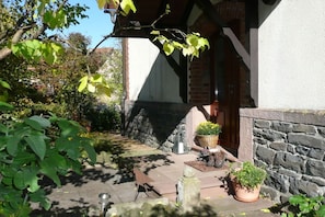 A stone building with a porch, potted plants, and outdoor seating. - Holiday apartment with 1 bedroom (Ehrenberg)