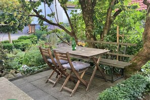 An outdoor wooden table with chairs, a bottle, and glasses. - Holiday apartment with 1 bedroom (Ehrenberg)
