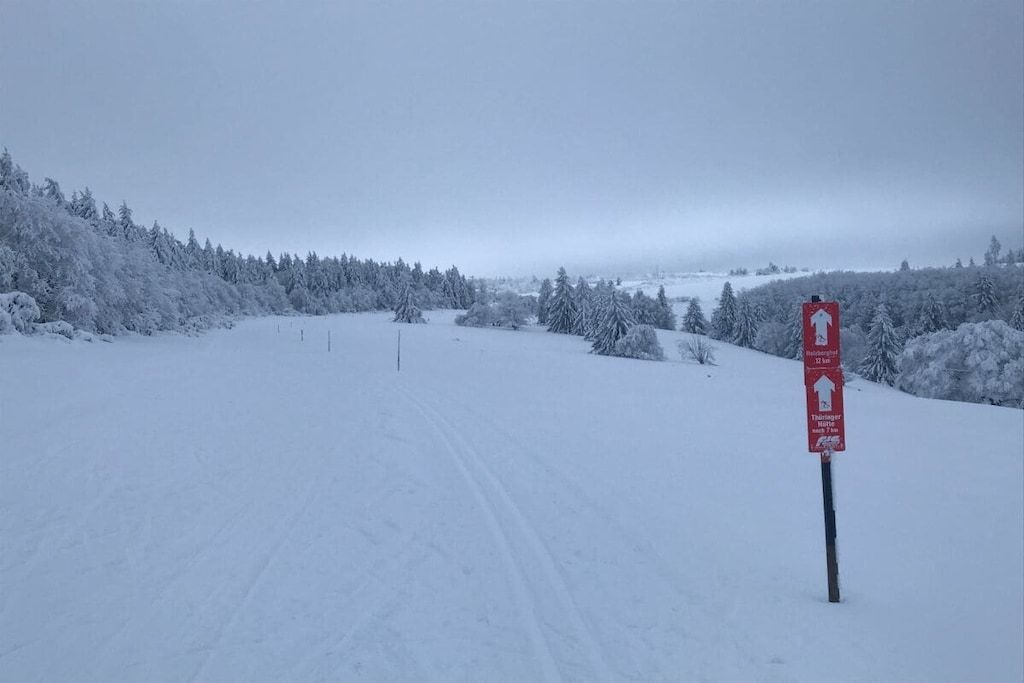 Un paysage enneigé avec un panneau indiquant un parcours de ski.