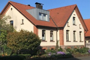 Een gebouw met twee verdiepingen, voorzien van een dak met rode tegels, een dakvenster en een gevel van baksteen.