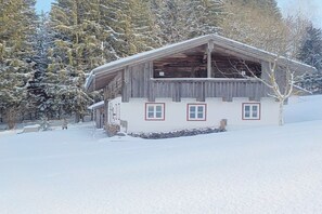 A wooden cabin with a sloped roof, surrounded by snow-covered trees. - Holiday apartment with 1 bedroom (Konzell)