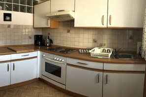 A kitchen with white cabinets, a stove, a coffee maker, and a sink. - Holiday apartment with 1 bedroom (Schönau am Königssee)