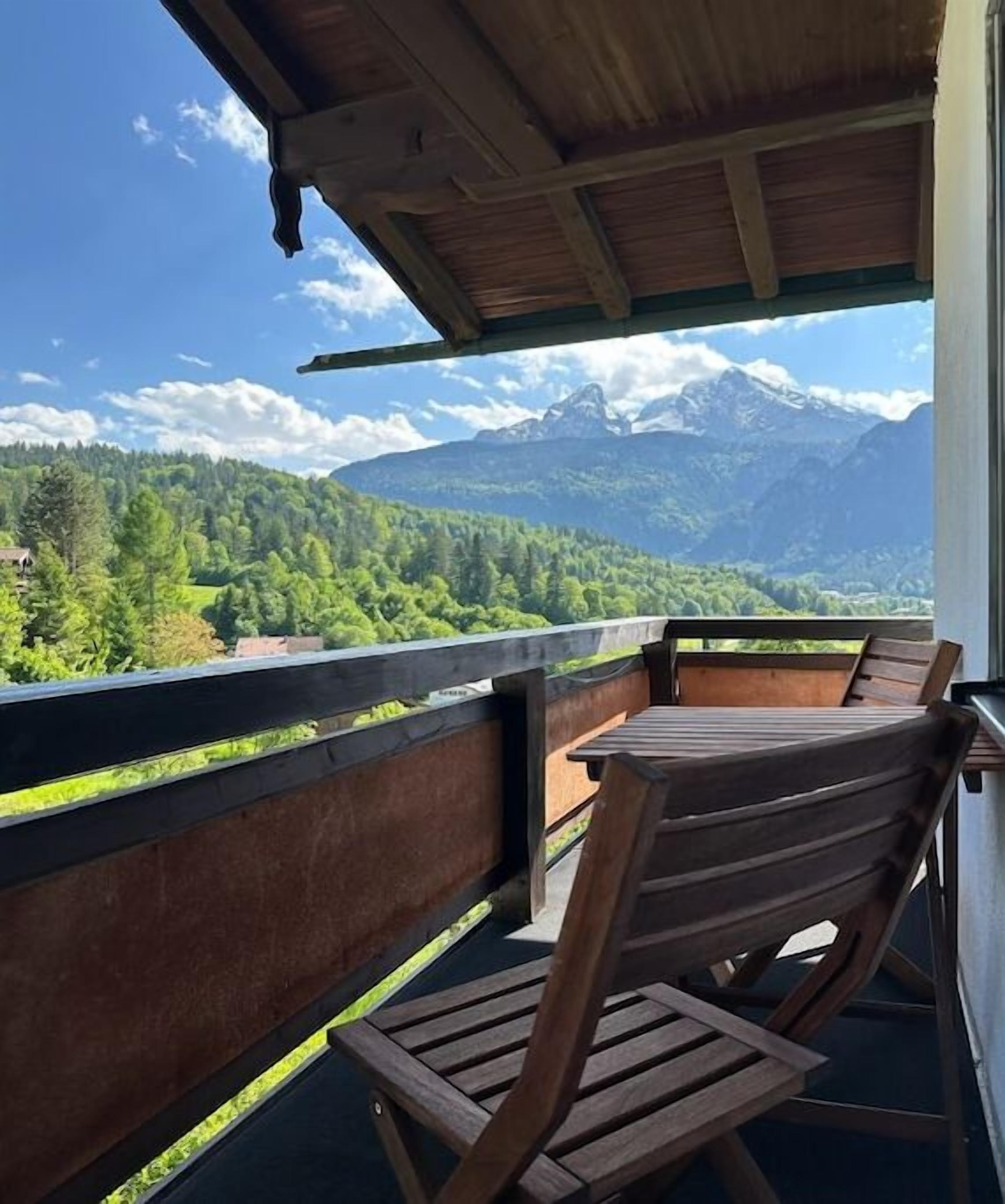 Un balcon avec des chaises en bois et une vue sur un paysage montagneux.