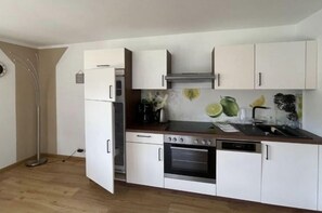 A compact kitchen with white cabinets, a built-in oven, and a dishwasher. - Holiday apartment with 1 bedroom (Schönau am Königssee)