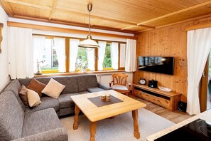 A cozy living room with a sofa, a coffee table, a television, and a wooden ceiling. - Holiday apartment Wörndle (Garmisch-Partenkirchen)