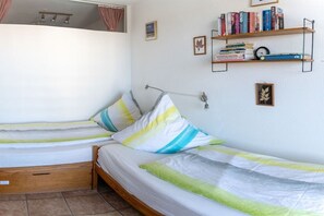 Ein Schlafzimmer mit zwei Betten, einem Bücherregal und einer kleinen Uhr.
