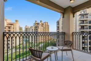 A balcony with two chairs and a table, overlooking a residential area with multiple apartment buildings. - Resort style 2 bedroom by Jumeirah Beach (Dubai)