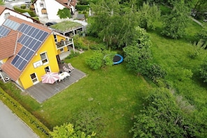 Ein Wohnhaus mit Solaranlage auf dem Dach, einem Trampolin und einer Terrasse mit Gartenmöbeln.