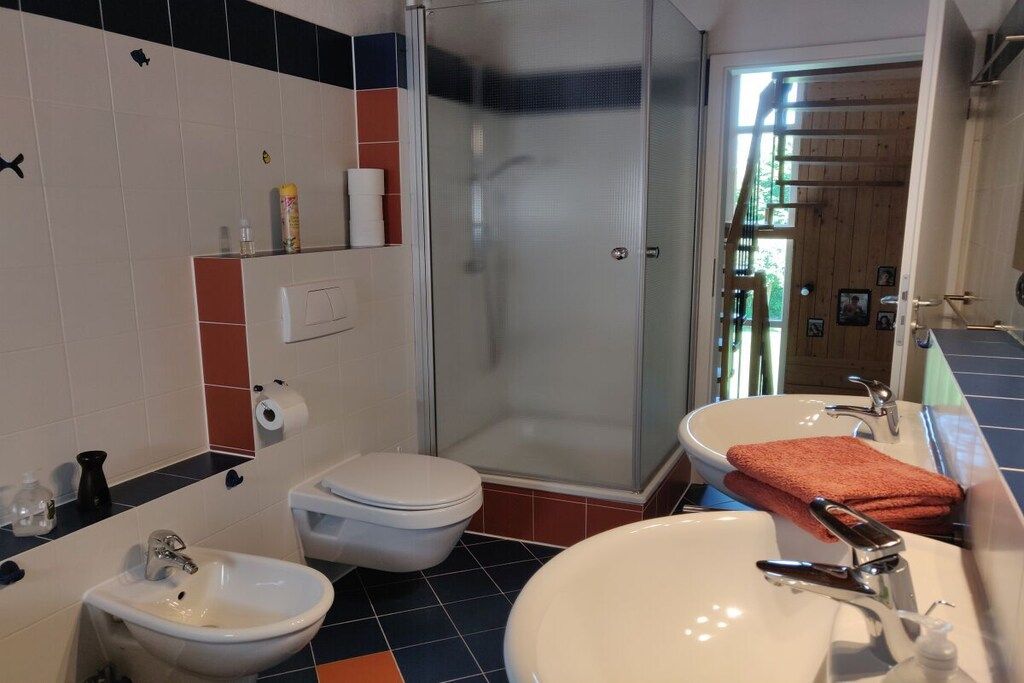Et badeværelse med bruser, toilet, håndvask og toiletbidét.