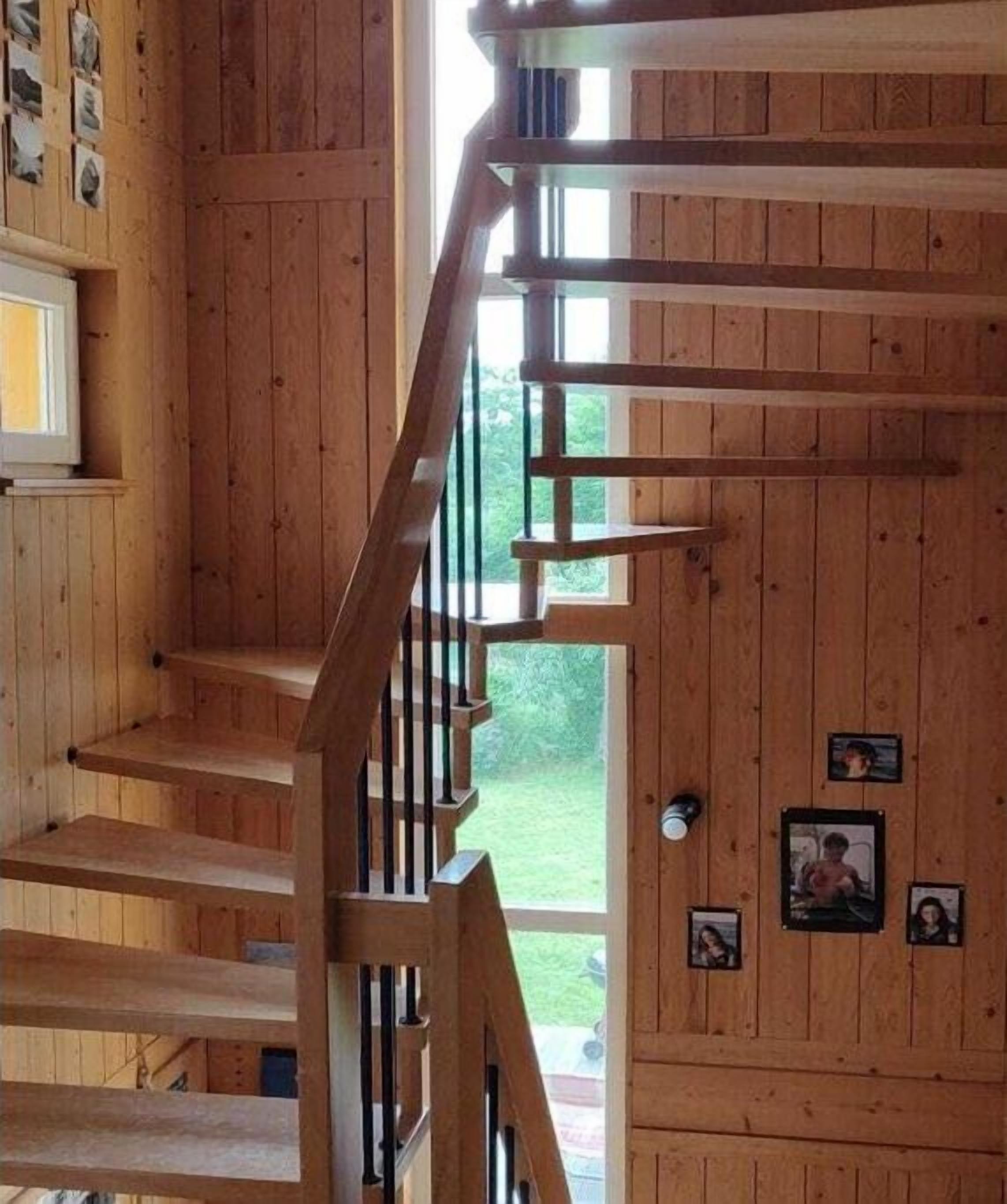 Eine Holztreppe mit Geländer, die zu einer oberen Etage führt.