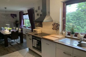 Una cocina moderna con comedor, una ventana con cortinas y vistas a zonas verdes.