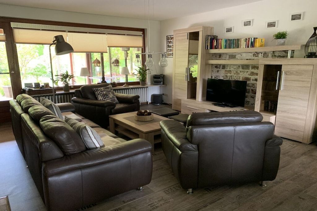 Ein Wohnzimmer mit einer Sofagarnitur, einem Couchtisch, einem Fernseher und einem Kamin.