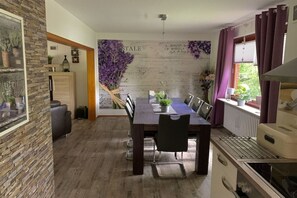 Een eethoek met een houten tafel, stoelen en een decoratieve wand met tekst en bloemen.