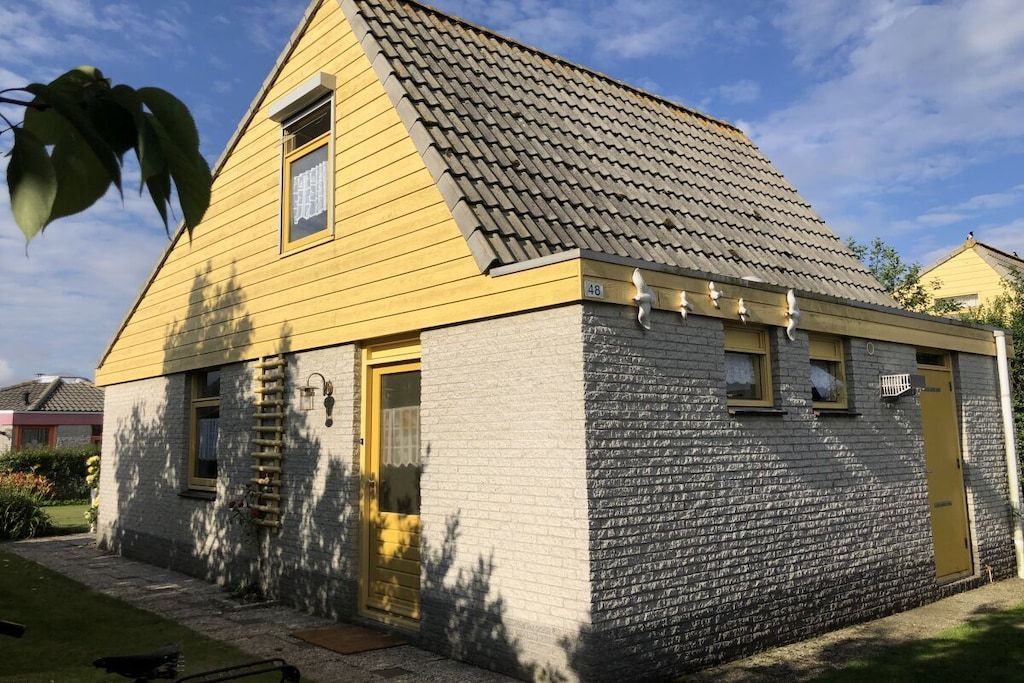 Un bâtiment à deux étages, avec une façade jaune et un toit gris.