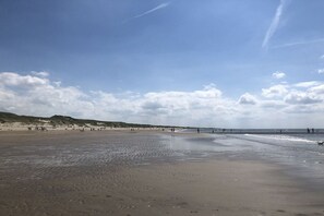 Une plage avec une vaste étendue de sable, une mer calme et un ciel dégagé.