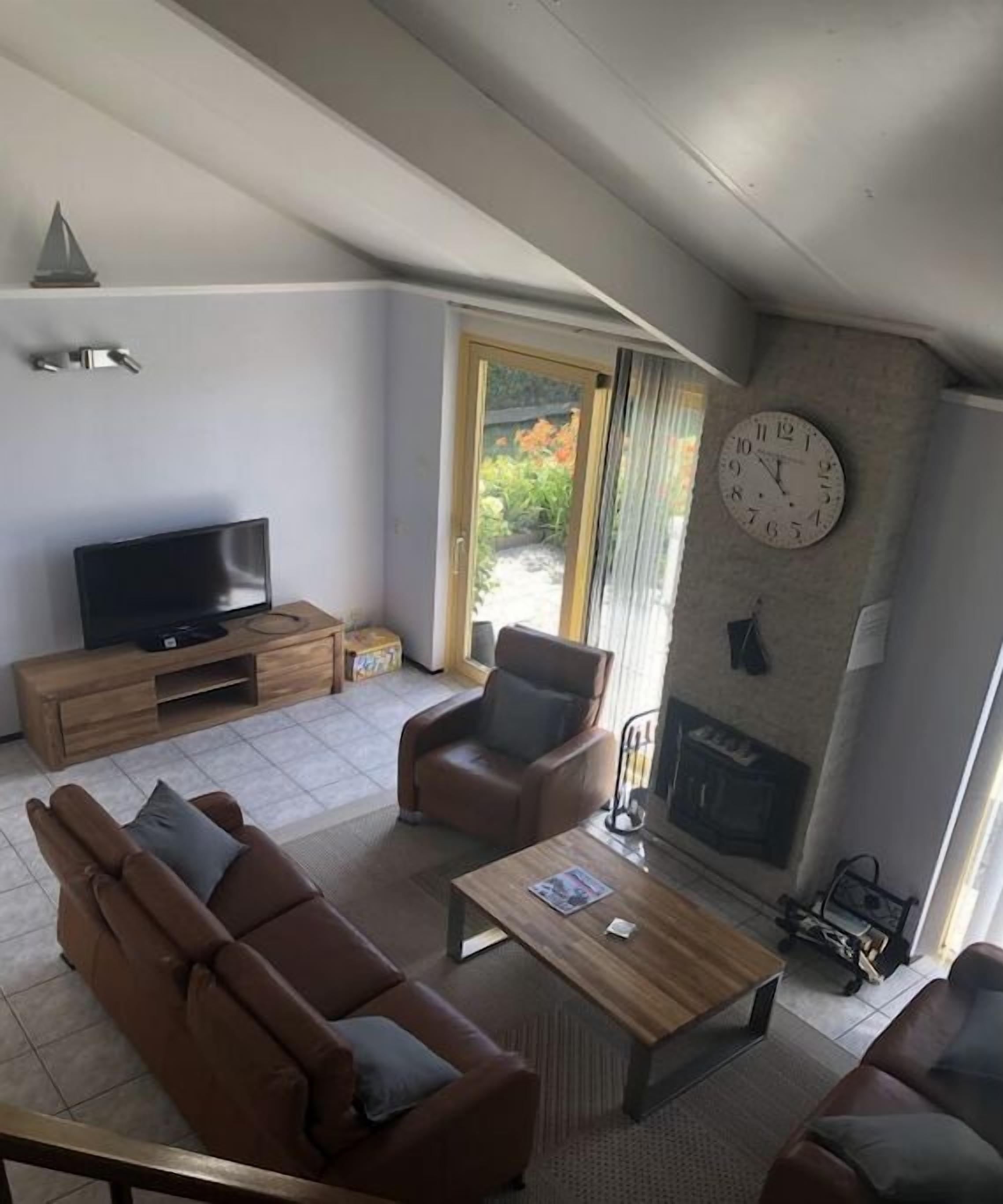 A modern living room with a sofa, armchairs, a coffee table, a flat-screen TV, and a fireplace.