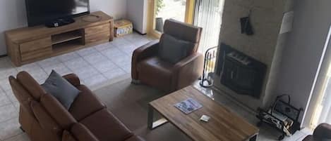 A modern living room with a sofa, armchairs, a coffee table, a flat-screen TV, and a fireplace.