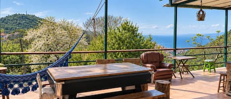 Une terrasse extérieure avec un hamac, des sièges et une vue sur la mer.