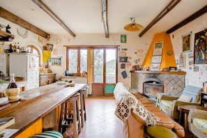 A rustic kitchen with a wooden bar, a fireplace, and a dining area with a bench. - Ara Solis (AROLA-PREAZZANO)