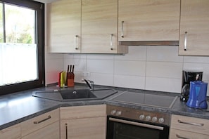 A kitchen with light wood cabinets, a double sink, a stove, and a coffee maker. - Holiday home in Allgäu with 2 bedrooms (Lechbruck)