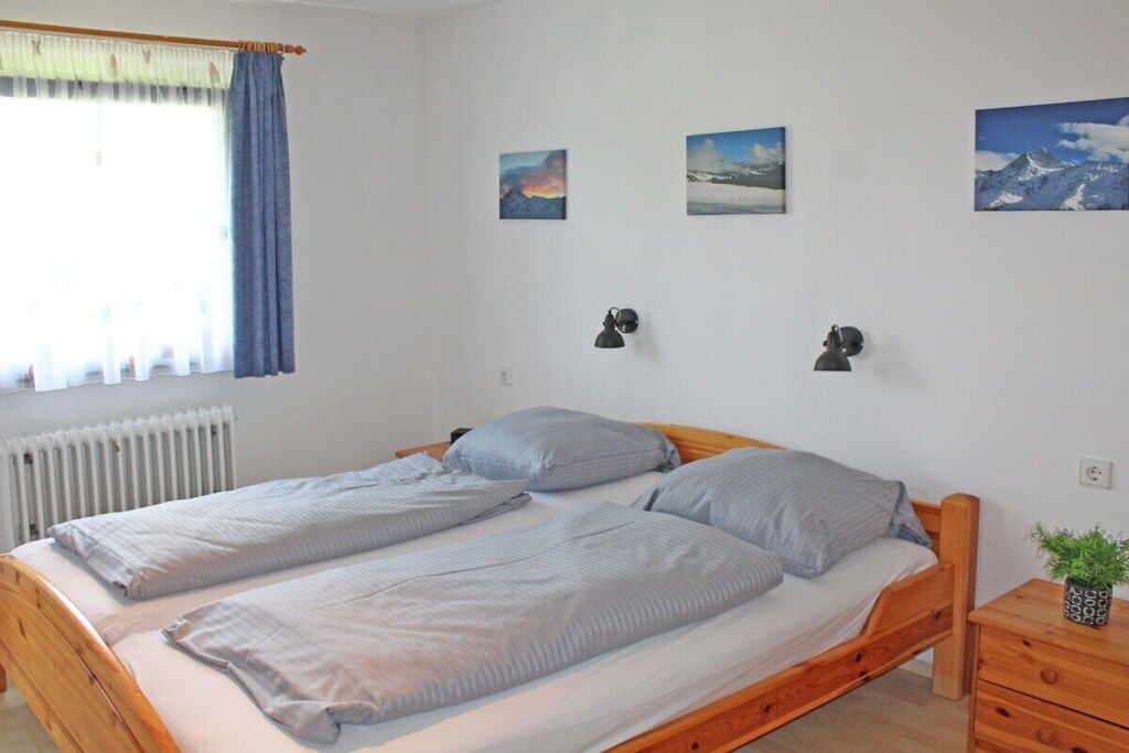 Ein Doppelbett mit Holzrahmen, zwei Nachttische und ein Fenster mit Vorhängen.