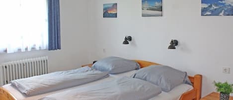 A double bed with a wooden frame, two bedside tables, and a window with curtains.
