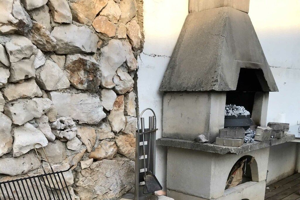 A stone wall and a concrete outdoor oven structure.