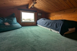 A small, cozy room with a single bed, a couch, and a window providing a view of the outside. - with garden directly on the water (wooden house) (Lemmer)