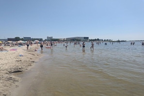 A crowded beach with people in the water and on the sand. - with garden directly on the water (wooden house) (Lemmer)