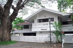 A white building with a balcony, a sign reading 'Vincent's', and a white picket fence.