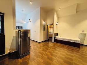 A compact hotel room with a kitchenette, a bed, and a small sitting area.