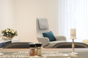A modern room with a grey armchair, a small table with a bowl of flowers, and a candle on a stand. - Holiday home with 3 bedrooms (Schliengen)