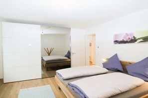 A modern bedroom with two beds, a wooden floor, and a white wardrobe. - Holiday home with 3 bedrooms (Schliengen)