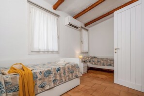 Ein Schlafzimmer mit zwei Betten, einem Fenster mit Vorhängen, einer Klimaanlage und einer Tür.