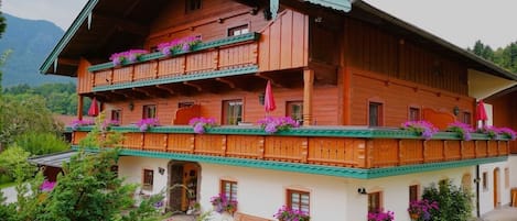 Una cabaña de madera con balcones, jardineras con flores y un camino de piedra.