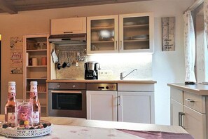 A kitchen with white cabinets, a coffee maker, and a clock on the wall. - Holzner-Hof "Hochgern" (Marquartstein)