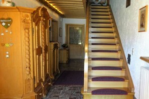 Una escalera de madera con una alfombra morada que lleva a una puerta.