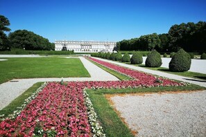A formal garden with symmetrical flower beds and a large building in the background. - Holzner-Hof "Hochgern" (Marquartstein)