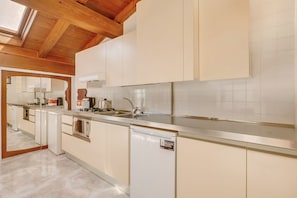 Eine moderne Küche mit weißen Schränken, einer Edelstahl-Arbeitsplatte und einem eingebauten Backofen.