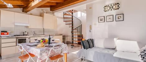 A compact living space with a kitchen, dining area, and a staircase leading to an upper level.