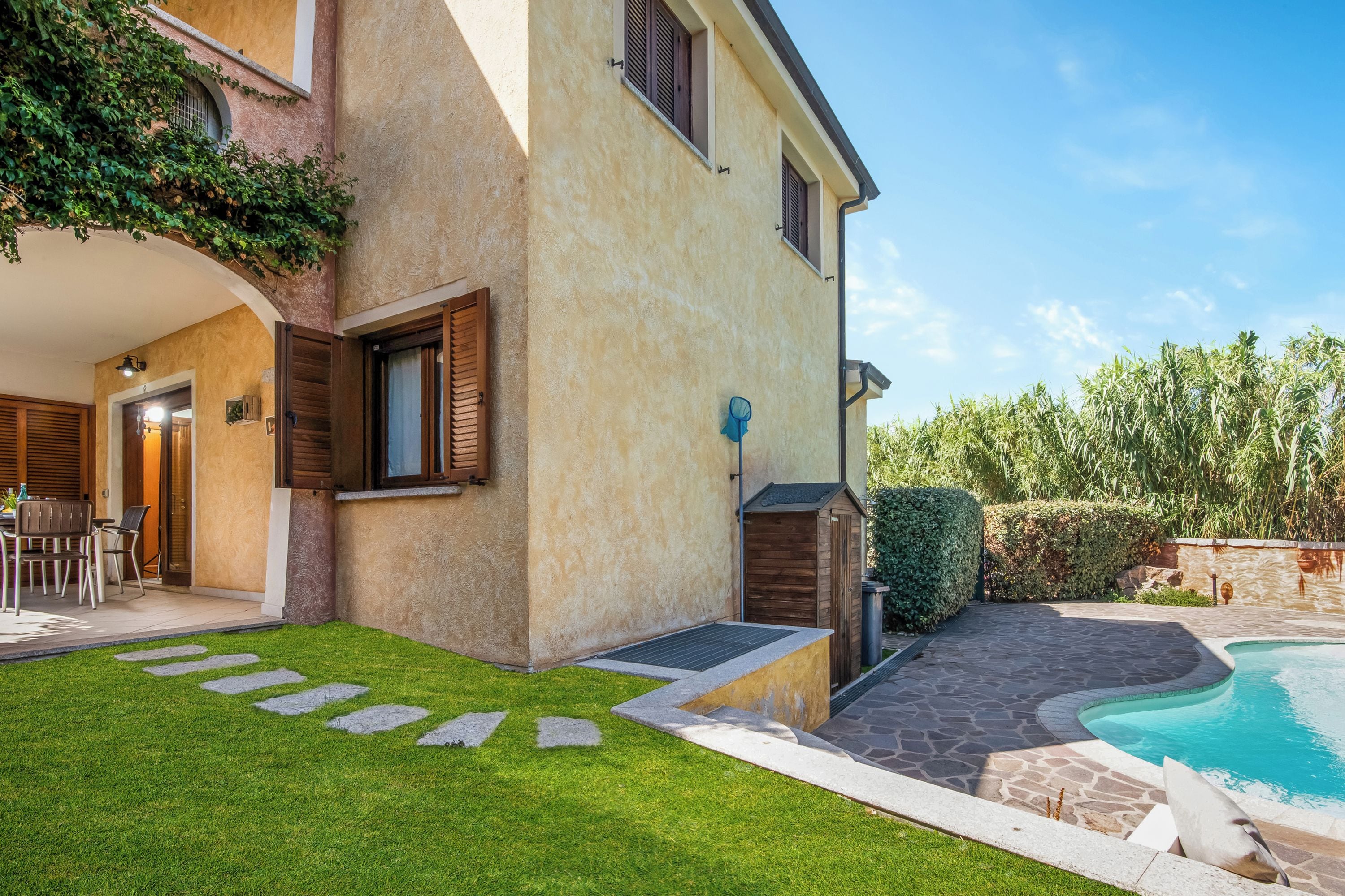 Une maison à deux étages avec une piscine, une pelouse bien entretenue et un chemin de pierres menant à l’entrée.