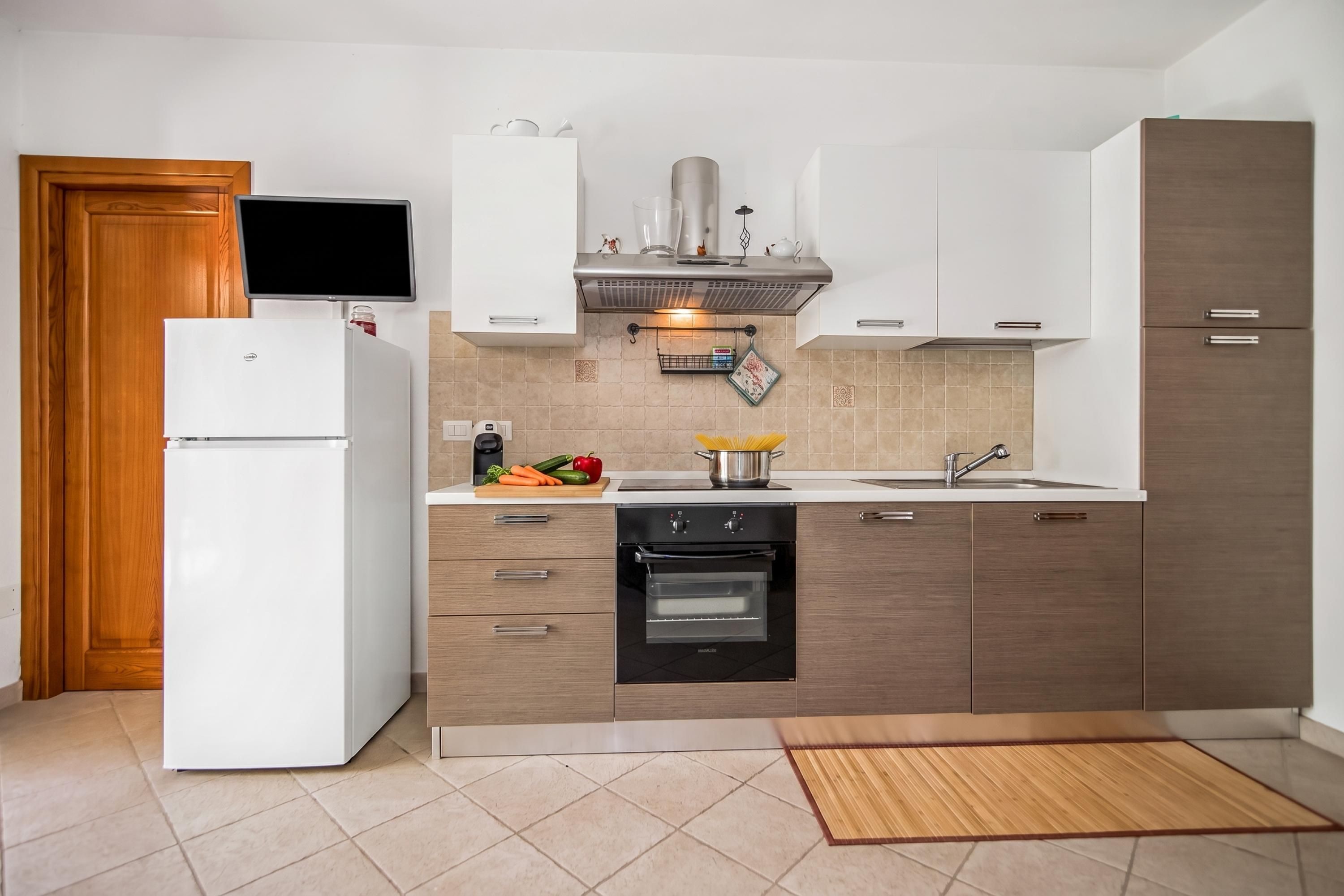 A modern kitchen with a built-in oven, a microwave, and a refrigerator.