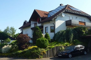 A two-story house with a sloped roof, solar panels, and a car parked in the driveway. - Holiday apartment with 2 bedrooms (Hilders)