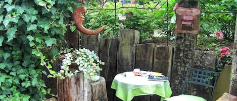 A garden with a table and chairs, surrounded by greenery and a wooden fence.