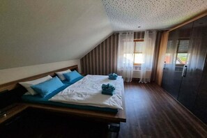 Une chambre à coucher avec un lit, une tête de lit en bois, une fenêtre avec des rideaux et une porte.