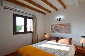 A bedroom with a bed, a window, a wall-mounted artwork, and a ceiling fan. - Finca in Muro with swimming pool (Muro)