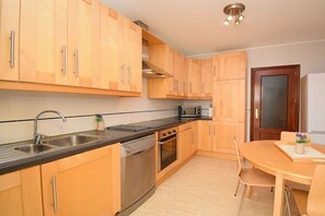 A kitchen with wooden cabinets, stainless steel appliances, and a dining area with a table and chairs. - Terraced house with 1 bedroom (Sa Pobla)
