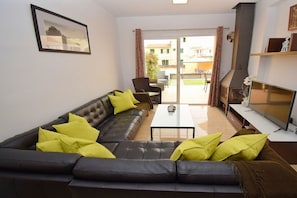 A living room with a sofa, coffee table, and a TV. There is a sliding glass door leading to an outdoor area with a table and chairs. - Terraced house with 1 bedroom (Sa Pobla)