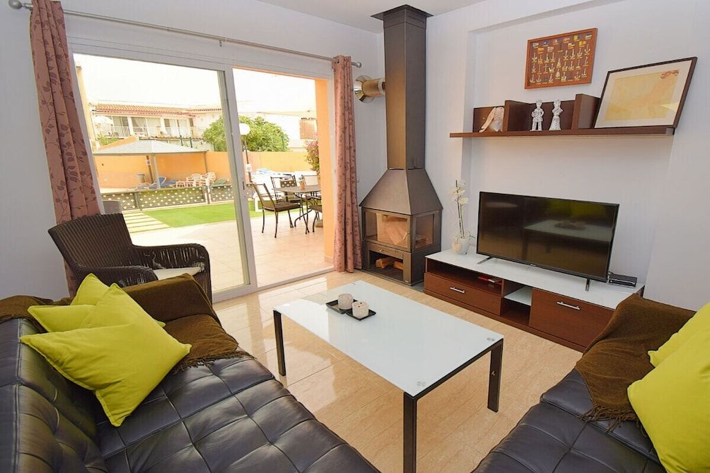 A living room with a sofa, a coffee table, a TV, a fireplace, and a sliding glass door leading to an outdoor area.