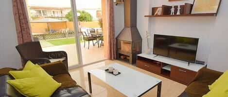 A living room with a sofa, a coffee table, a TV, a fireplace, and a sliding glass door leading to an outdoor area.